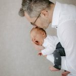 Papa küsst gähnendes Neugeborenes beim Babyshooting im Studio Lüdenscheid