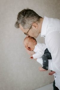Papa küsst gähnendes Neugeborenes beim Babyshooting im Studio Lüdenscheid